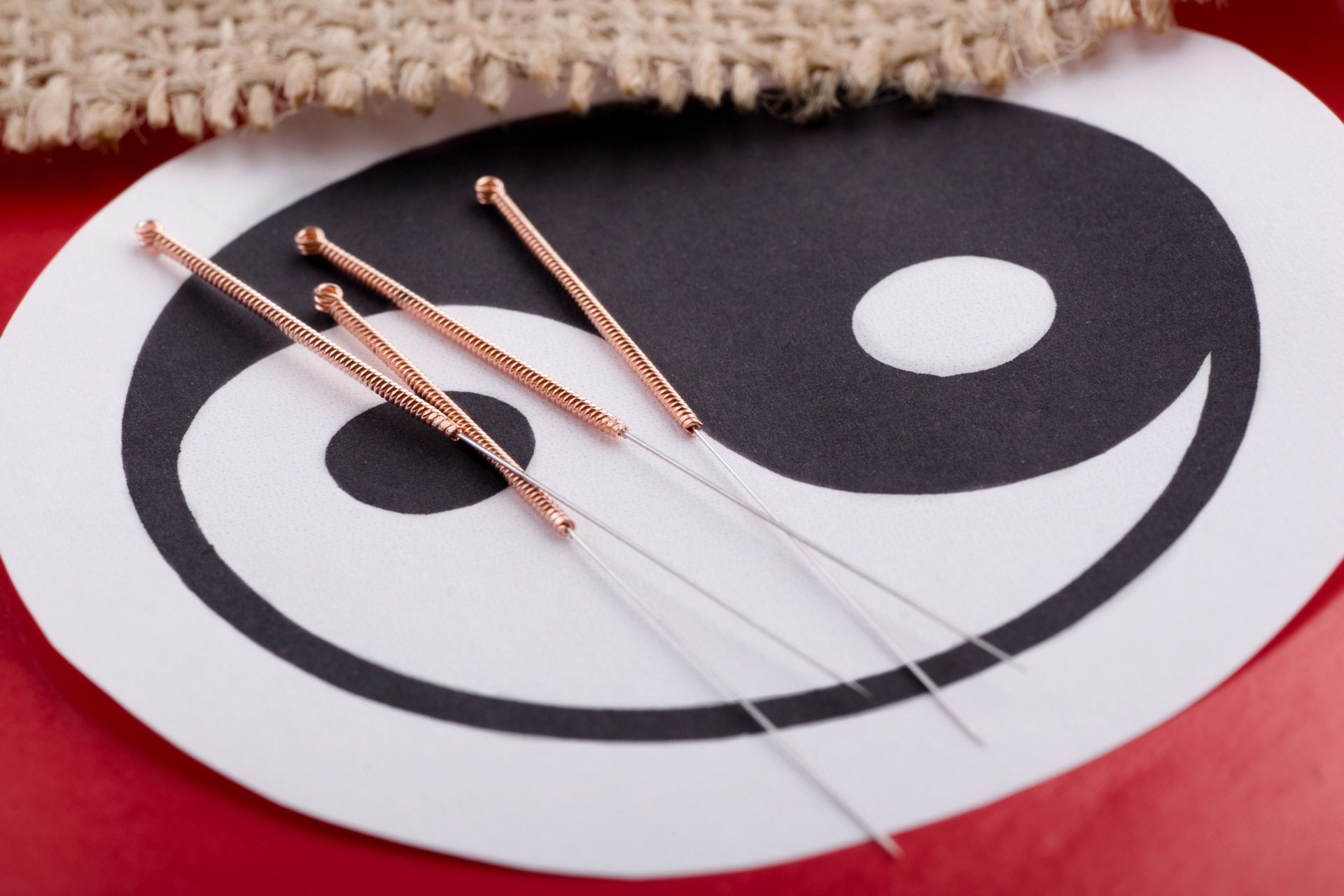 Four acupuncture needles are laying on a yin yang symbol