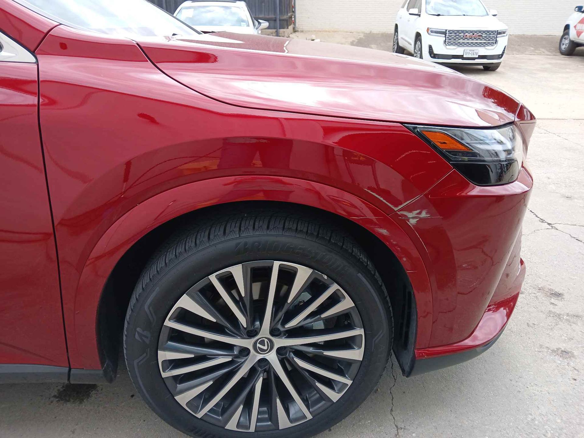 Close-up of a red SUV’s front wheel and fender in a parking lot