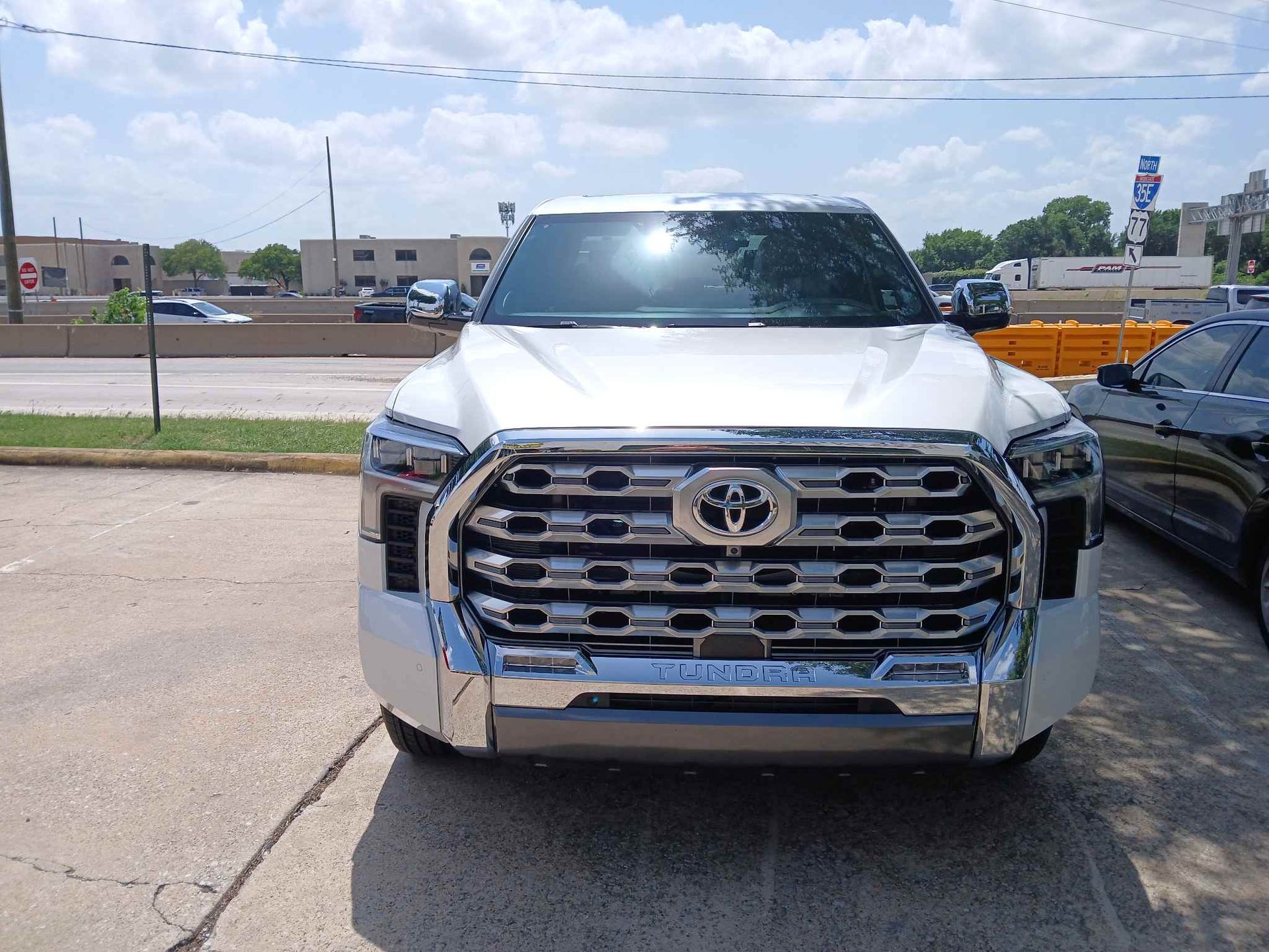 Front view of a white Toyota SUV parked on a roadside under bright daylight.
