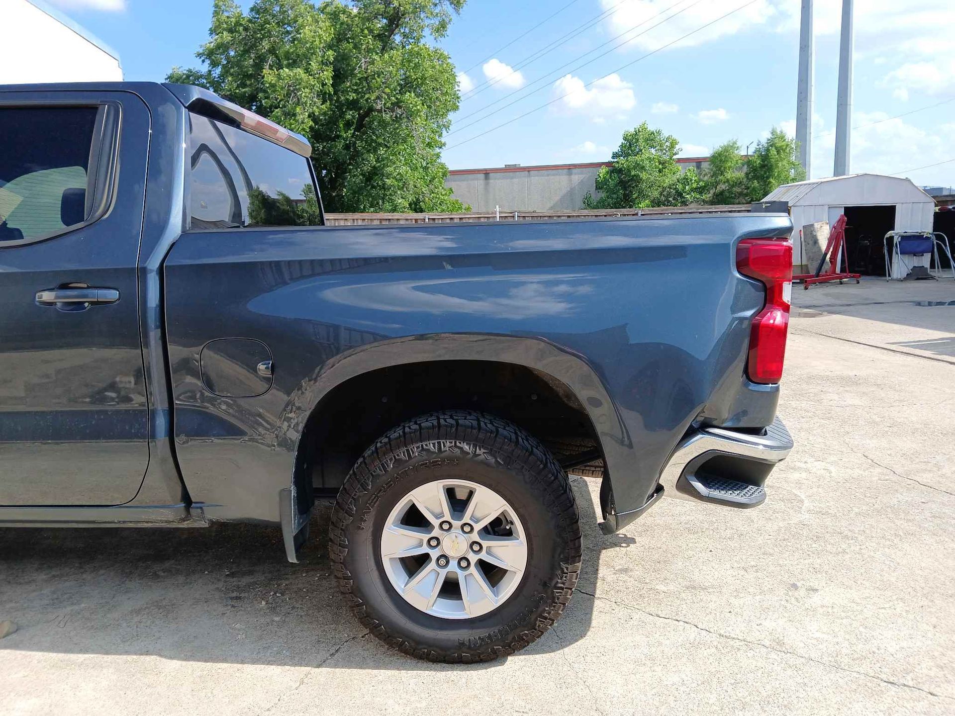 Dark gray pickup truck parked outdoors on a sunny day, side view of the rear half.