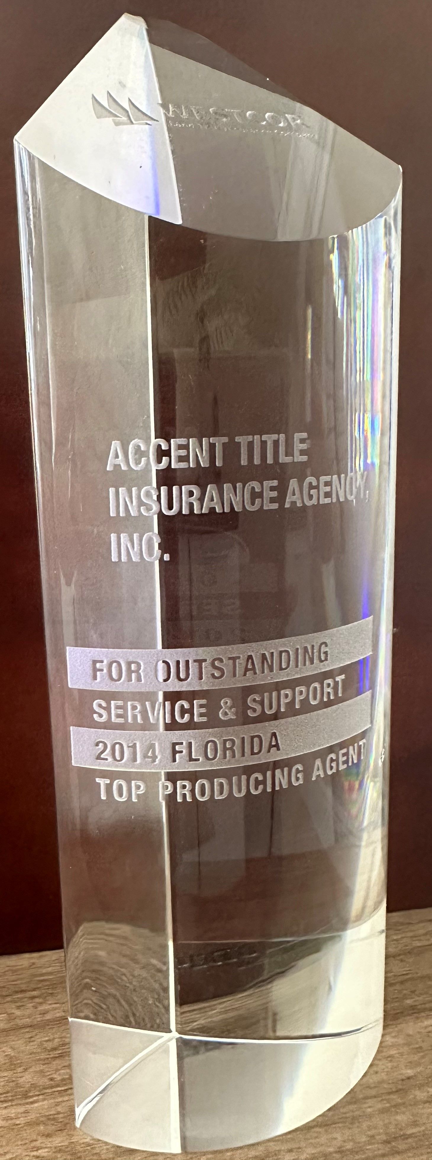 A clear glass trophy is sitting on a wooden table.