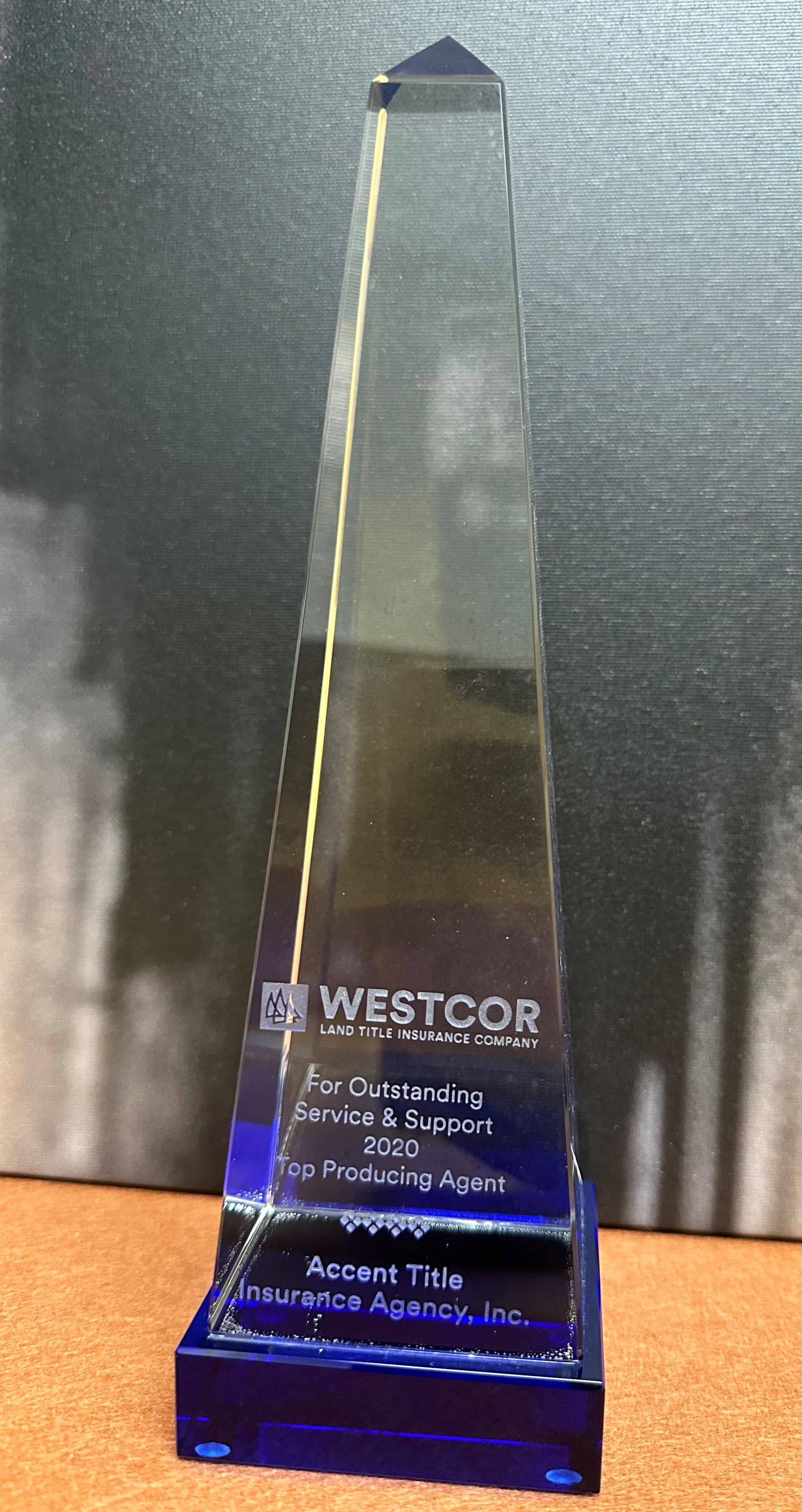 A blue obelisk shaped trophy is sitting on a table.