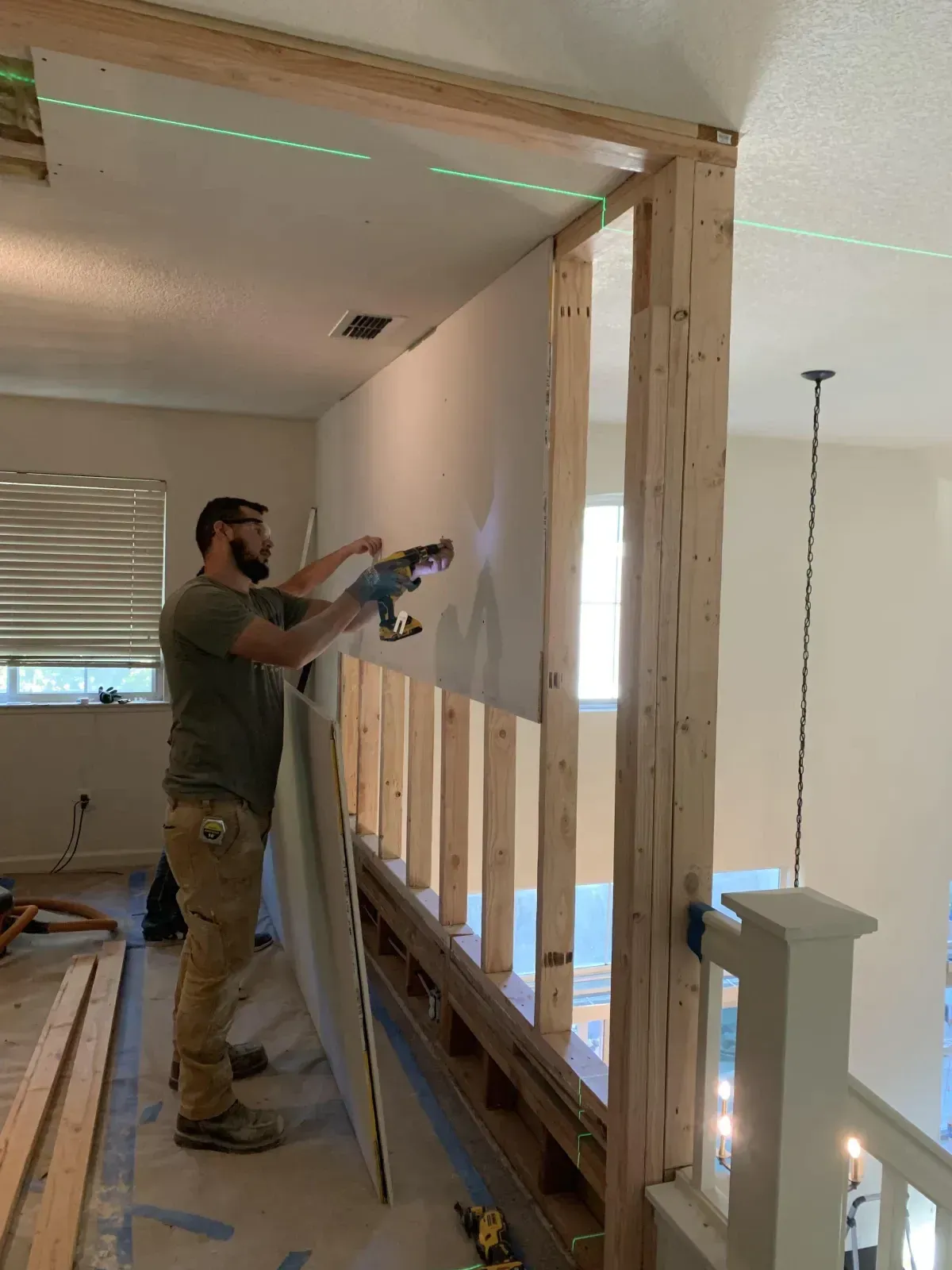 A man is standing in a room holding a piece of drywall.
