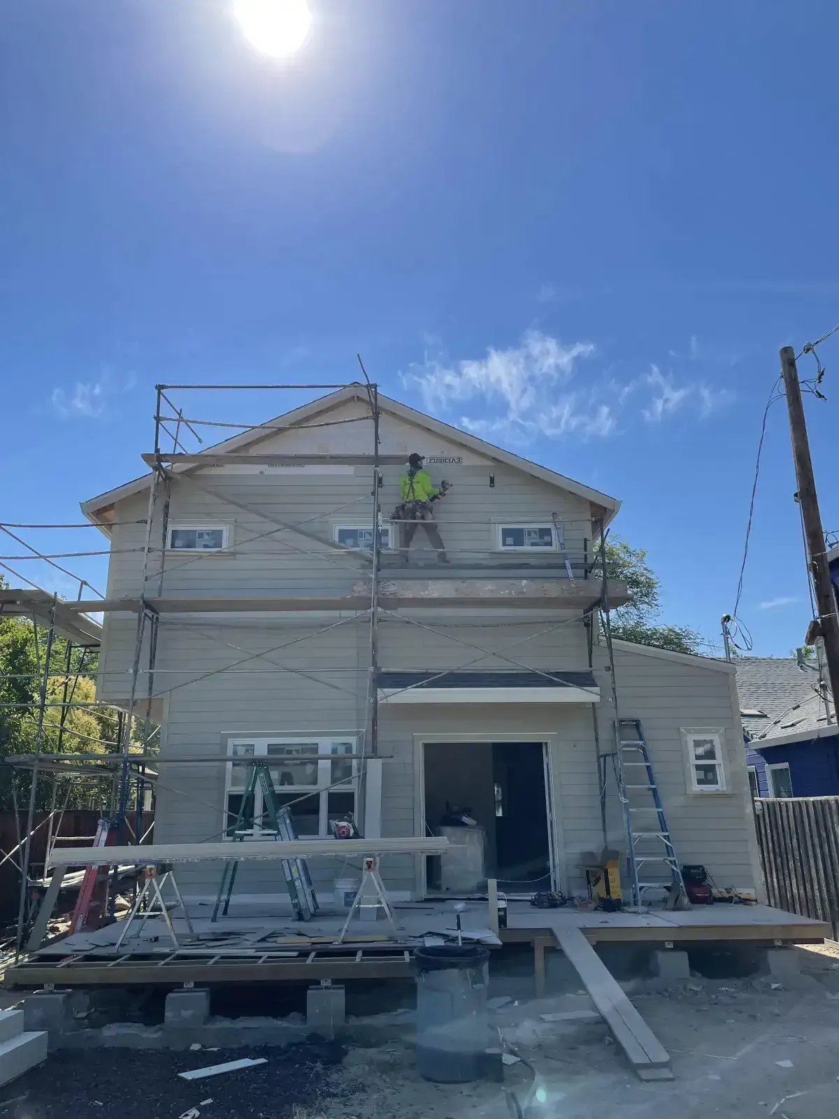 A man is painting the side of a house with scaffolding.