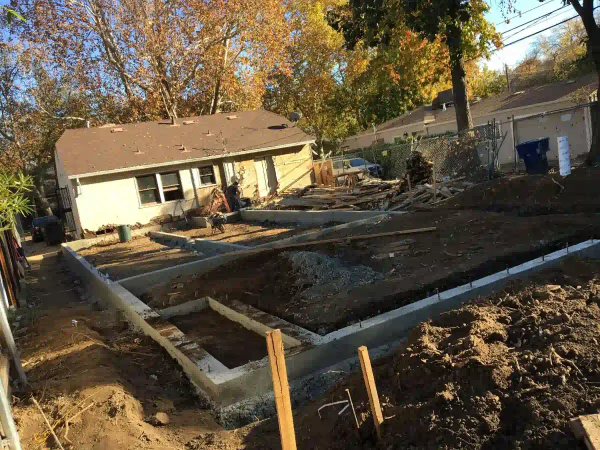 A house is being built in a backyard with a lot of dirt in front of it.