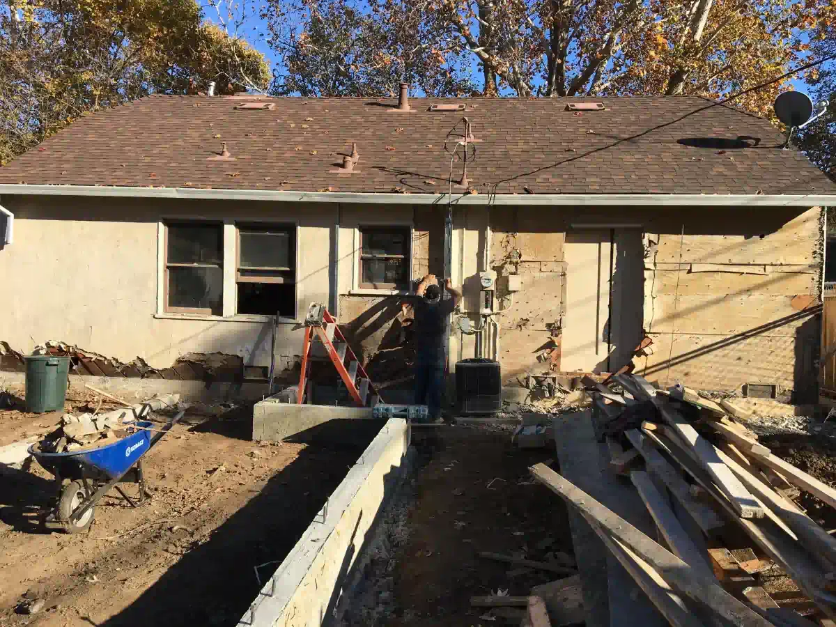 A man is standing in front of a house that is being remodeled