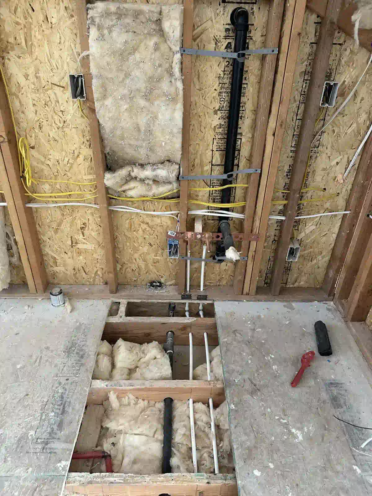 A bathroom under construction with pipes coming out of the ceiling.