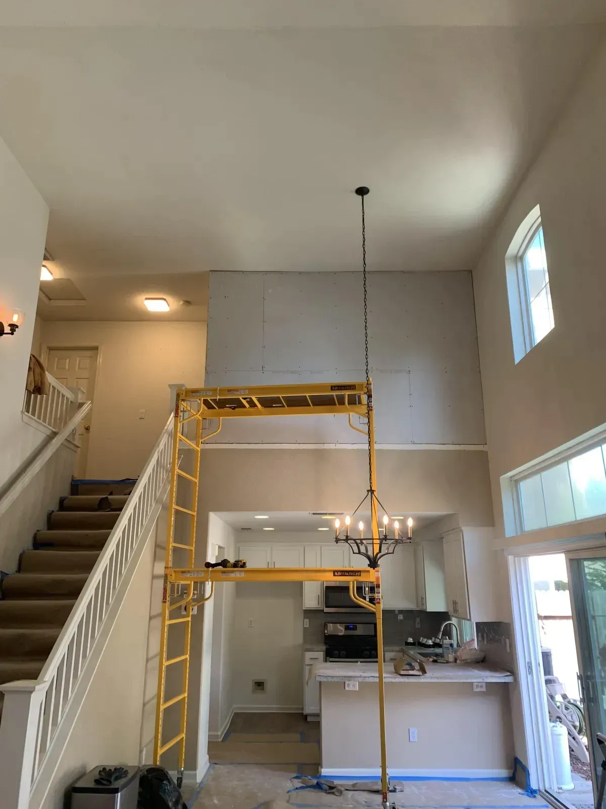 A kitchen with a staircase and a chandelier hanging from the ceiling.