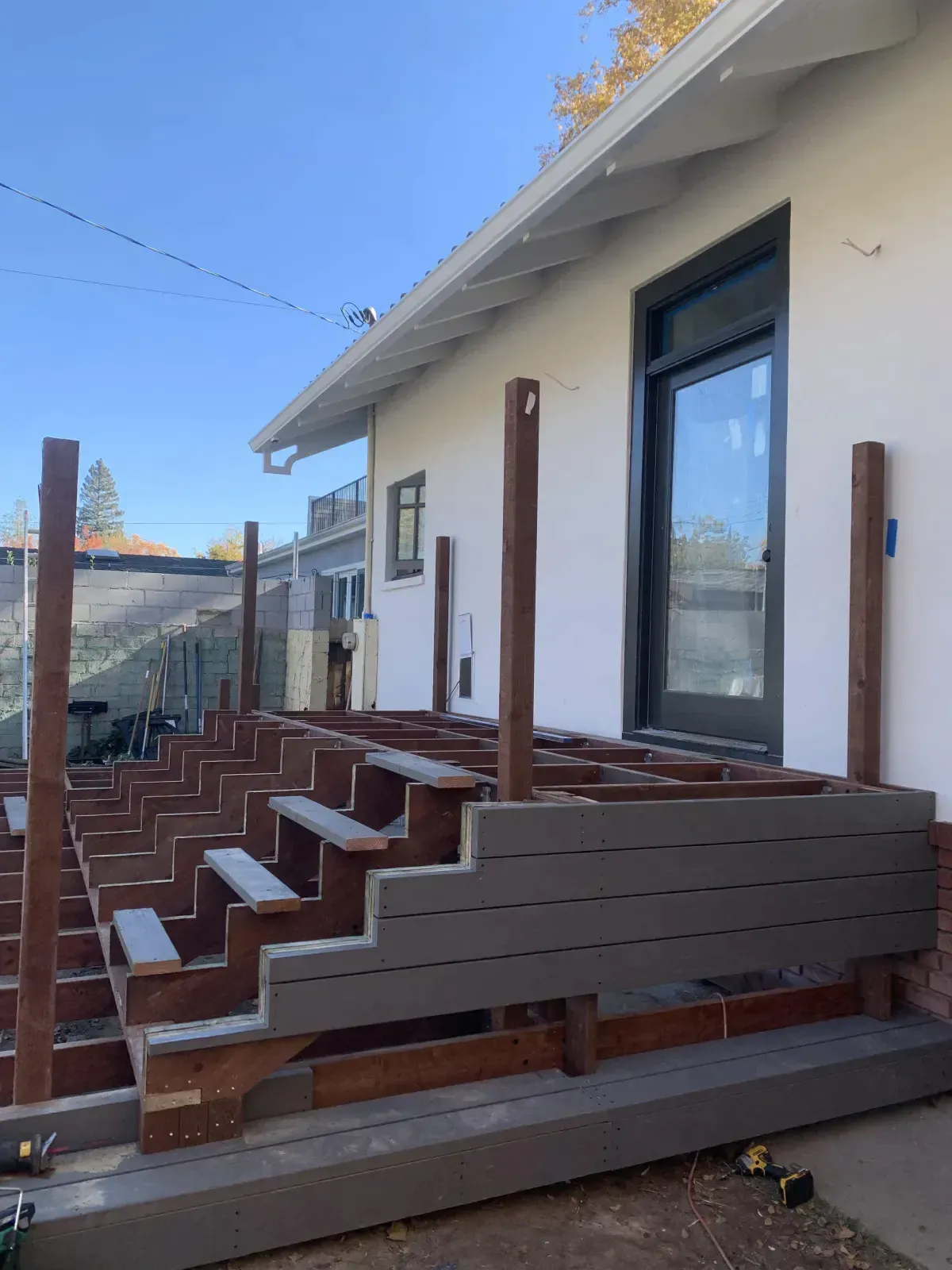 A wooden deck is being built in front of a house