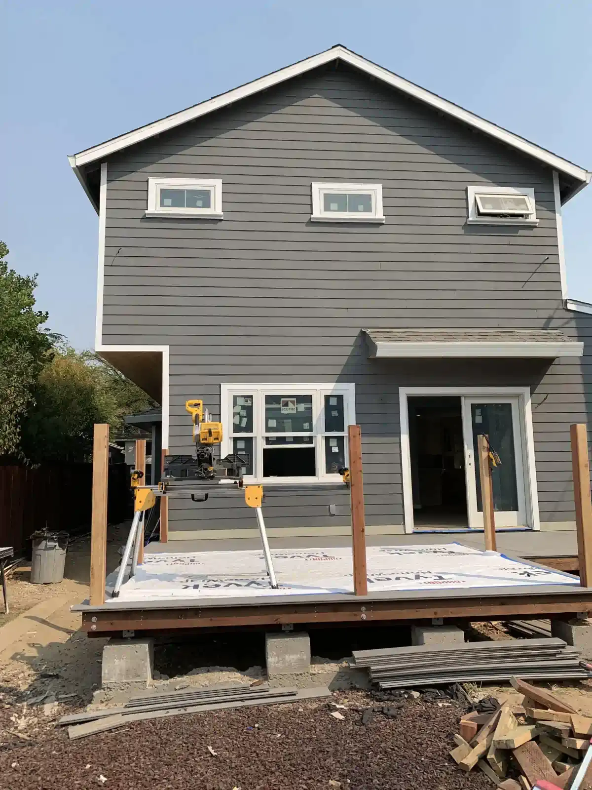 A gray house with a wooden deck in front of it.