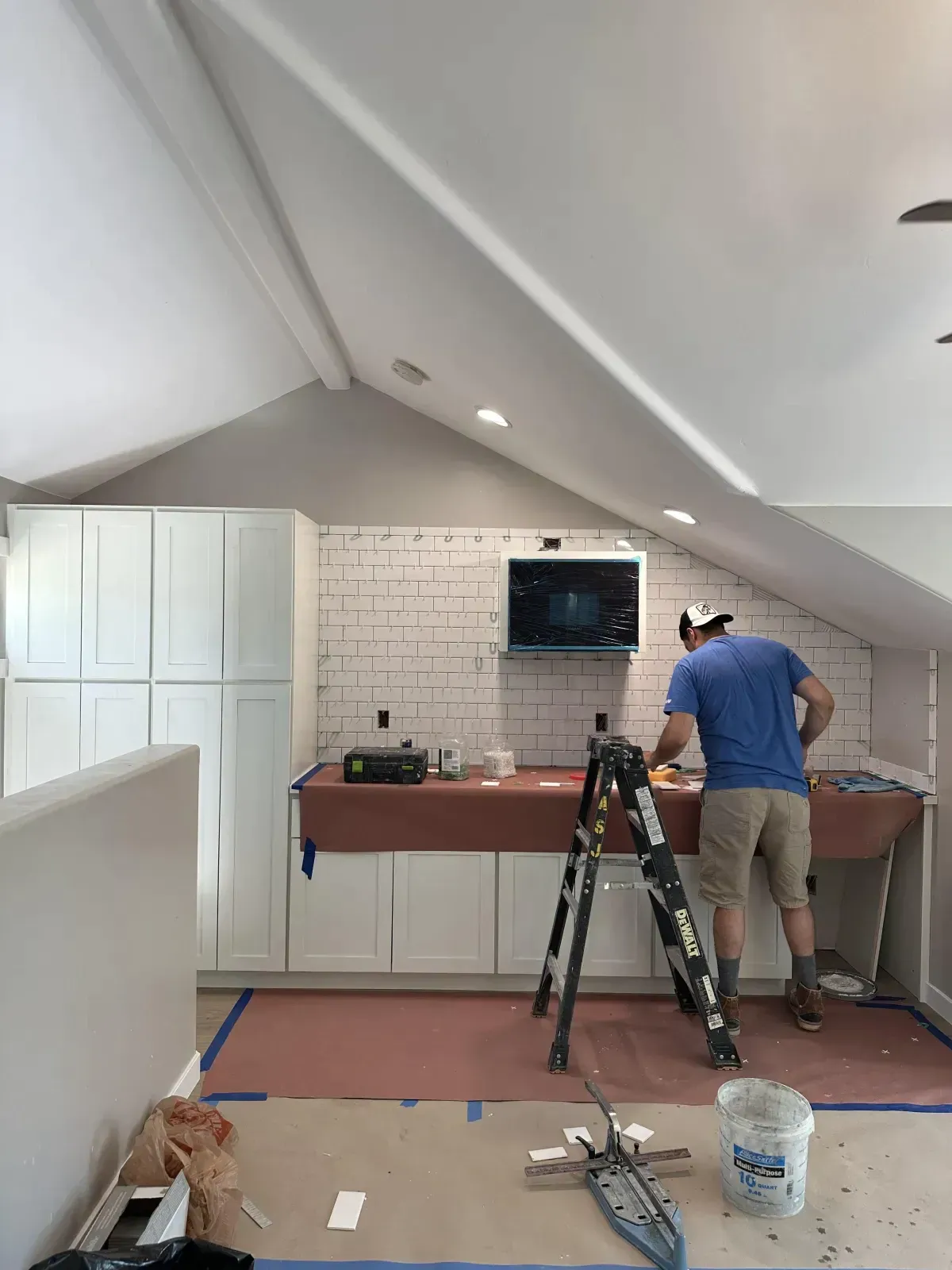 A man is standing on a ladder in a kitchen.