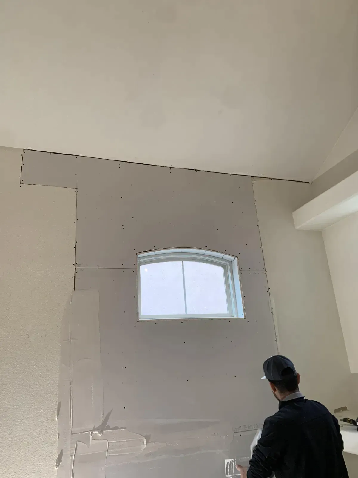 A man is standing in a room with a window in the wall.
