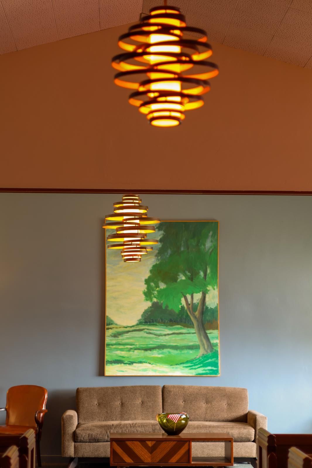 Cozy living room with a couch, coffee table, wall art, and a sculptural hanging light fixture.