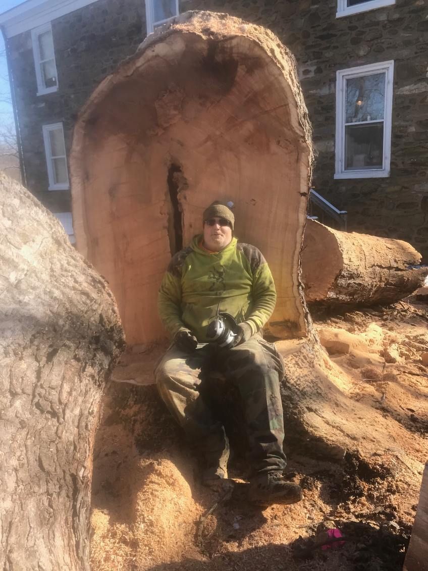 A man is sitting on a tree stump in front of a building.