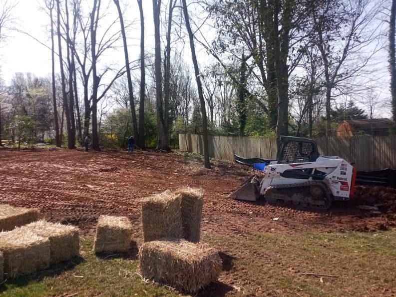 A bulldozer is moving hay bales in a field.