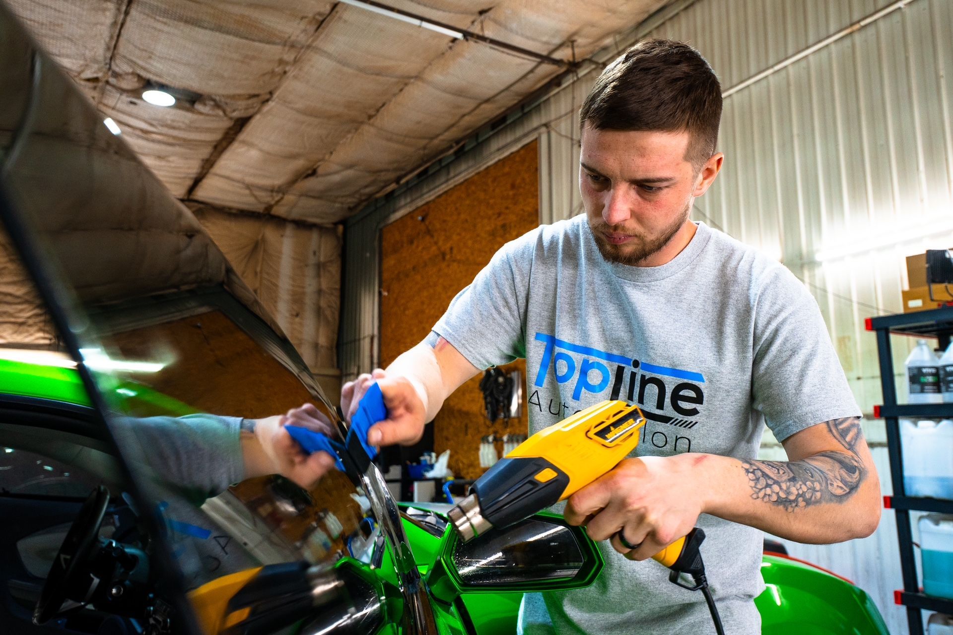 Mechanic using a blue tool to work on a green motorcycle in a garage