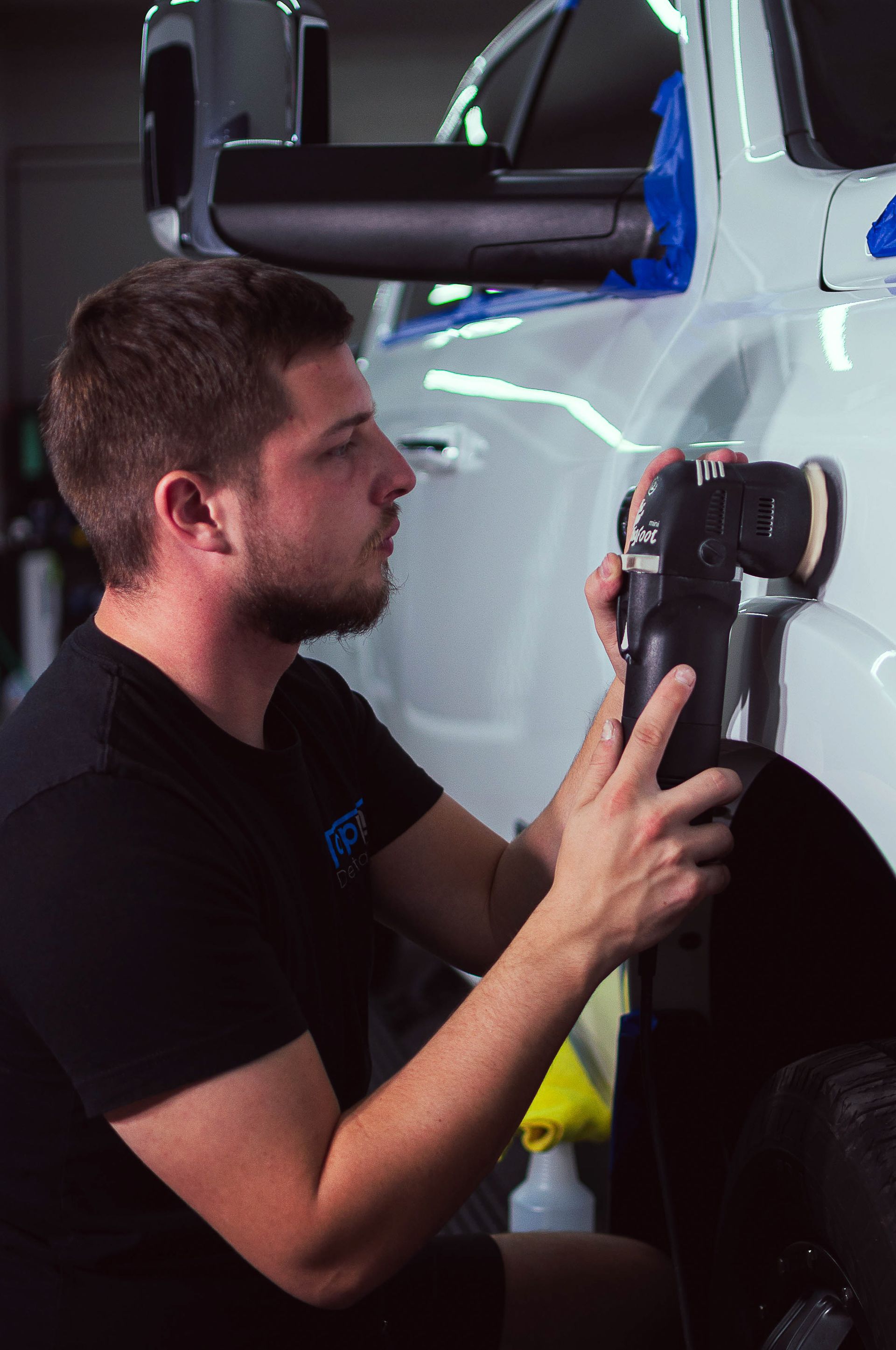 Technician using a suction dent repair tool on a white car door in a workshop