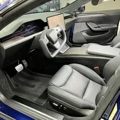 Luxury car interior with gray seats, steering yoke, and open driver-side door