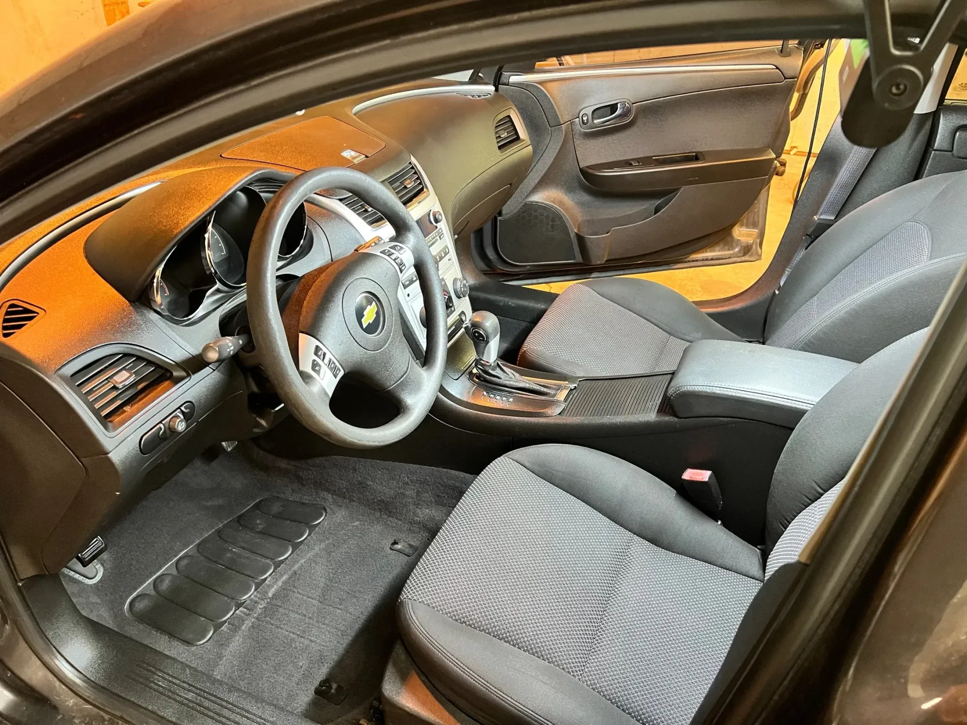 Car interior with gray seats, black dashboard, steering wheel, and orange wood trim accents