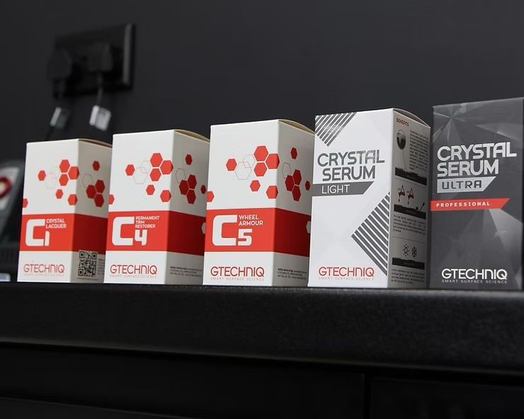 Four Gtechniq car care product boxes lined up on a black shelf, white and red packaging visible