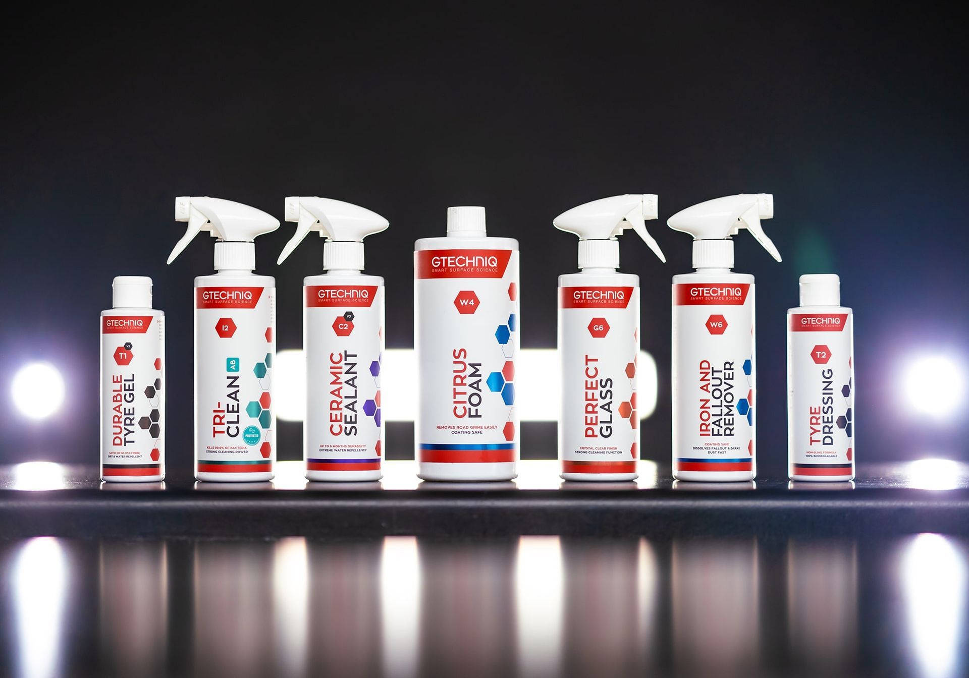 Row of white spray bottles and cleaning cans on a reflective surface with red and blue labels