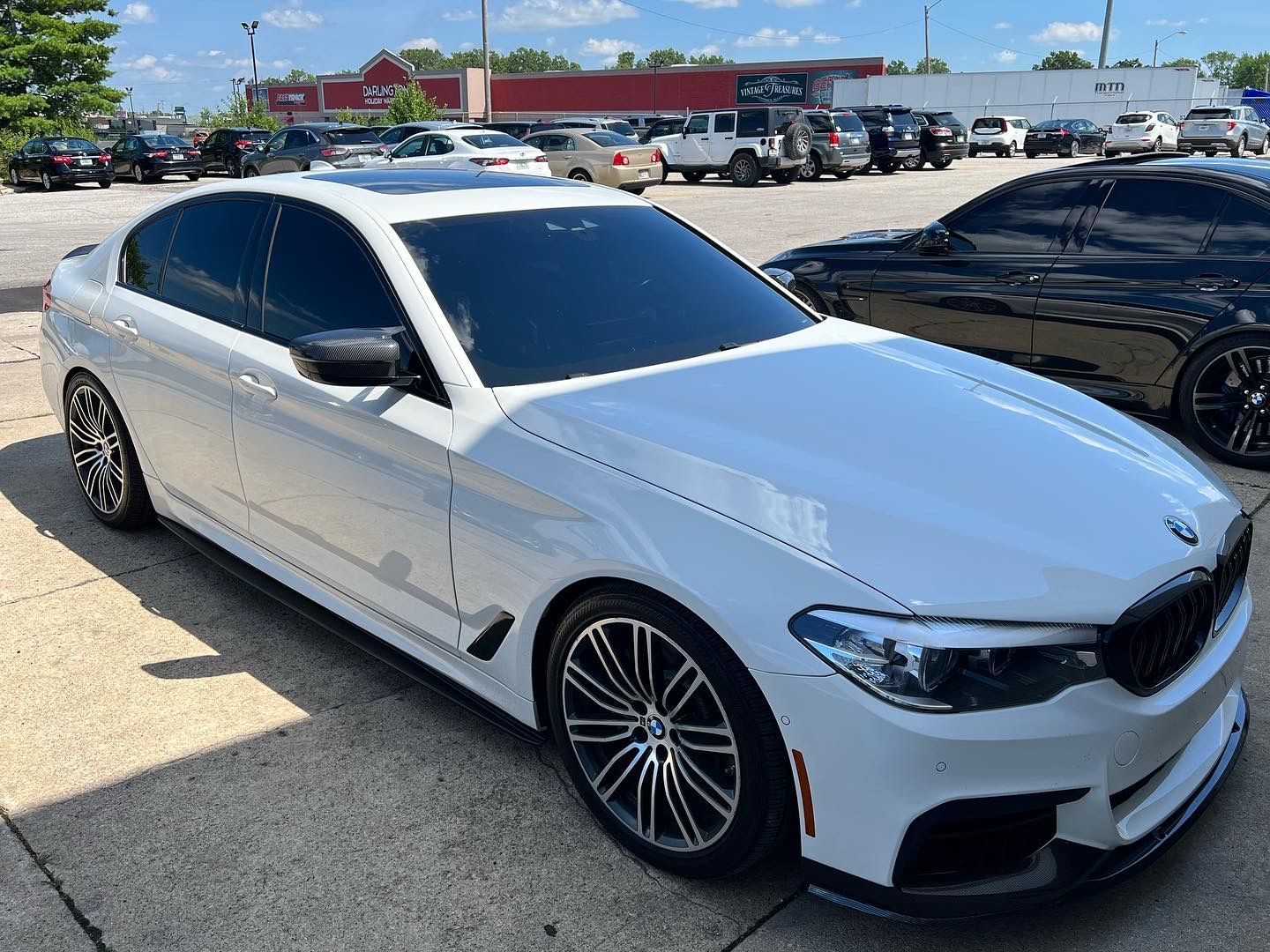 White BMW coupe parked in a dealership lot on a sunny day