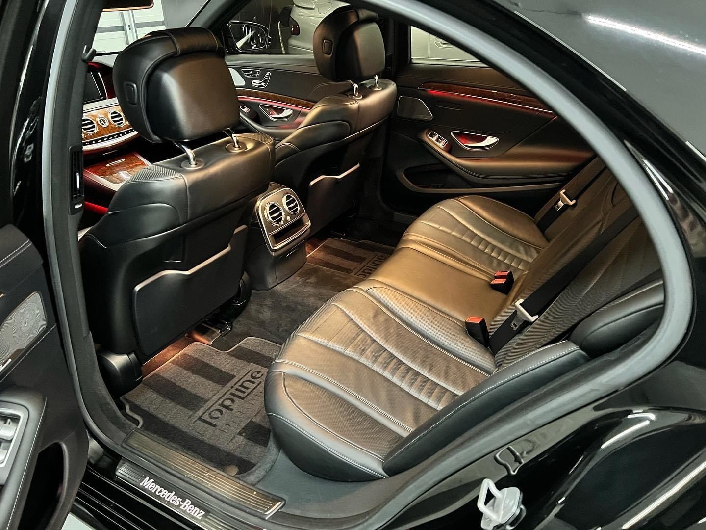 Luxury car interior with black leather rear seats, quilted upholstery, and red accent lighting