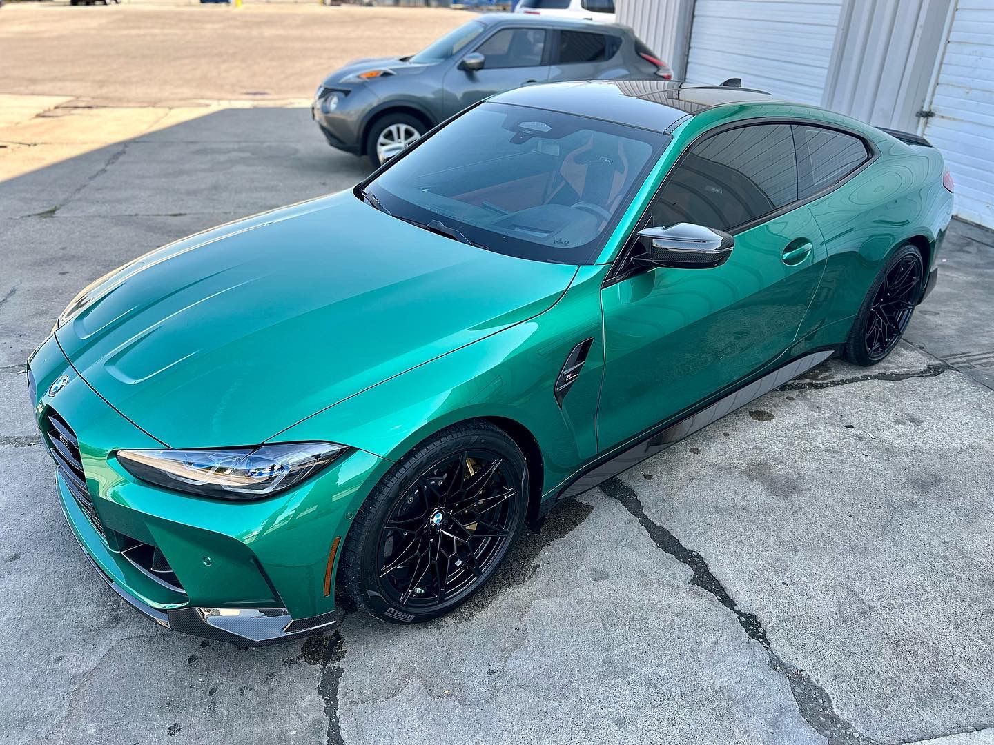 Teal sports coupe parked on a concrete lot, with a gray SUV in the background.