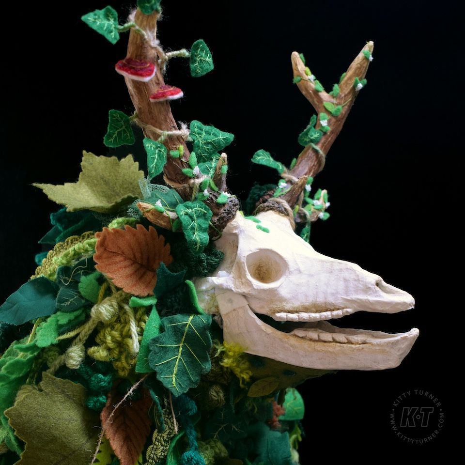 A creepy paper mache deer skull puppet covered in handmade textile leaves.