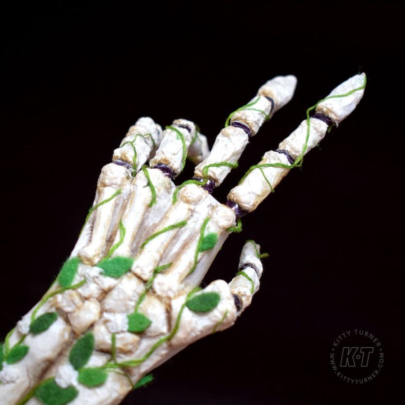 An articulated skeleton hand made from eco friendly paper mache covered in vines and felt leaves. 