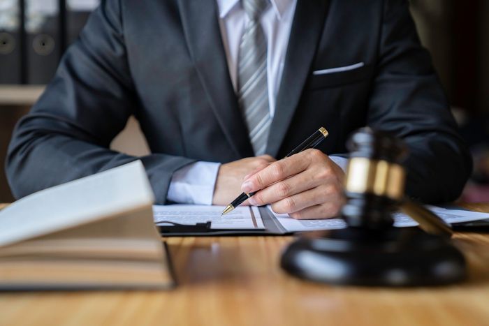 A man in a suit and tie is sitting at a table writing on a piece of paper.