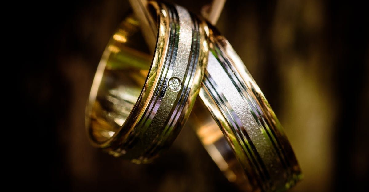 A close up of two wedding rings hanging on a wooden stick.