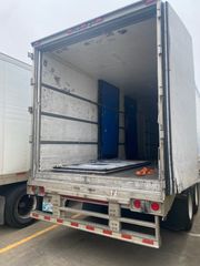 Open truck trailer with rear door raised, showing empty cargo space and blue interior panels.