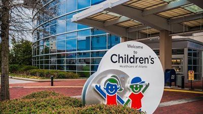 Children's Healthcare of Atlanta hospital entrance with sign and building with blue glass.