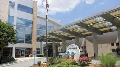 Exterior of a Children's hospital building with a covered entrance, sign, and American flag.