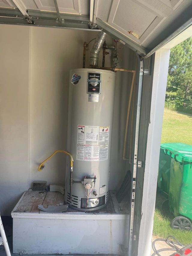 Water heater in a garage cabinet, with pipes and a small vent hose beside it.