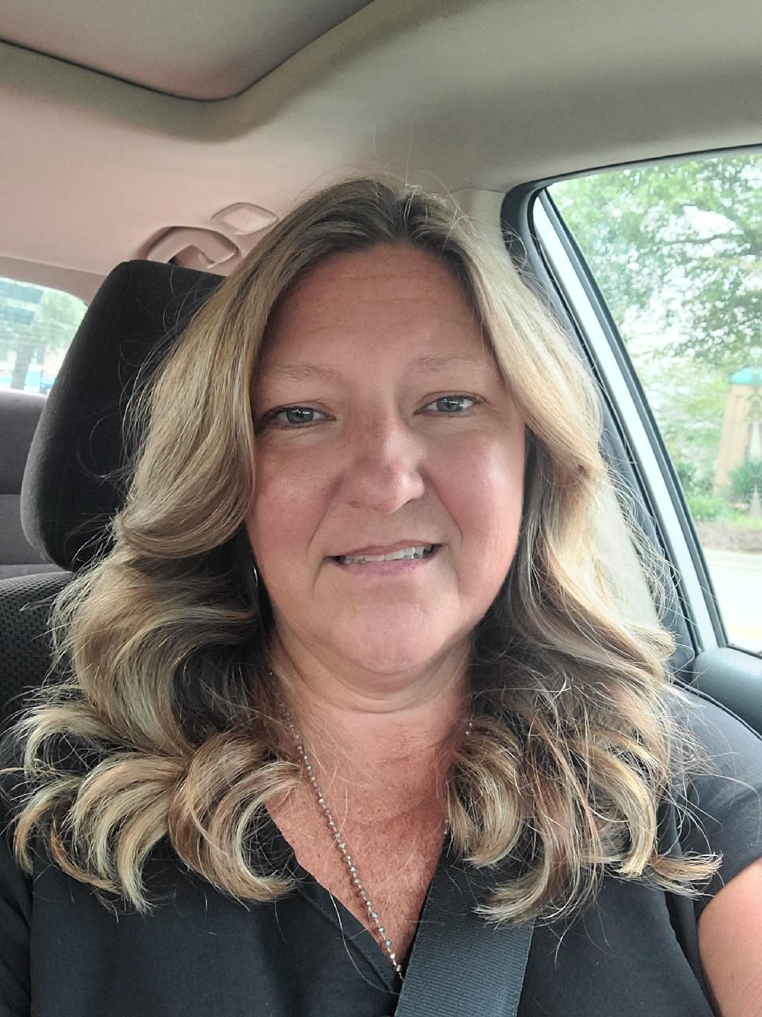 Family Friendly Dental Staff in Jacksonville and Supply NC A woman is sitting in a car wearing a seat belt and smiling.