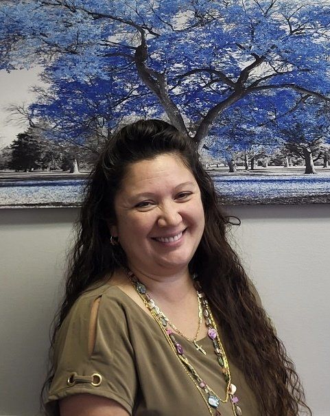 Visit Supply and Jacksonville NC's top family dental office A woman is smiling in front of a painting of trees.