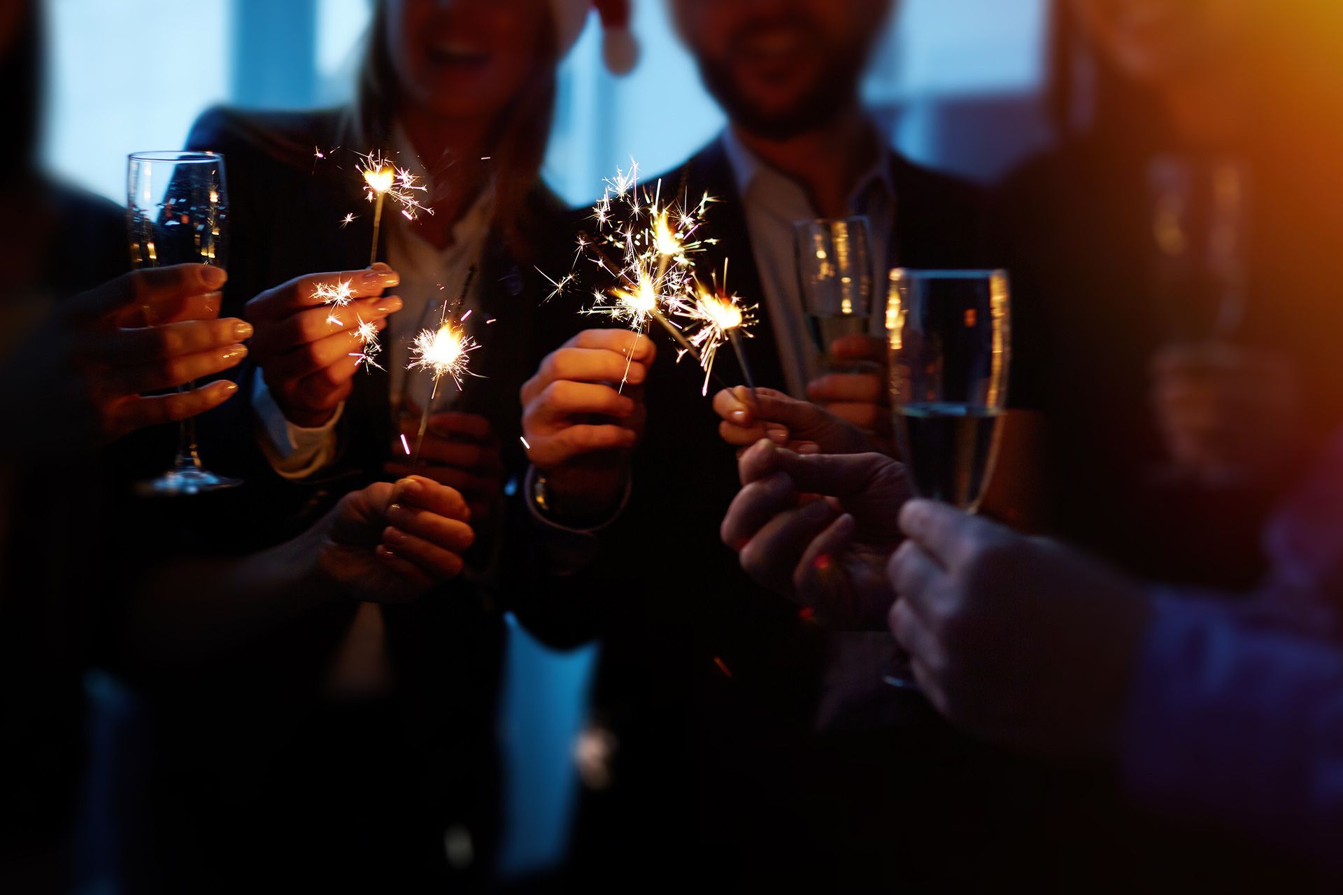People holding sparklers and champagne glasses in a dimly lit celebration