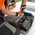 Technicians working on an open battery pack inside an electric vehicle component tray