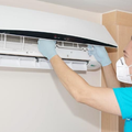 Technician in gloves cleaning the indoor unit of a wall-mounted air conditioner
