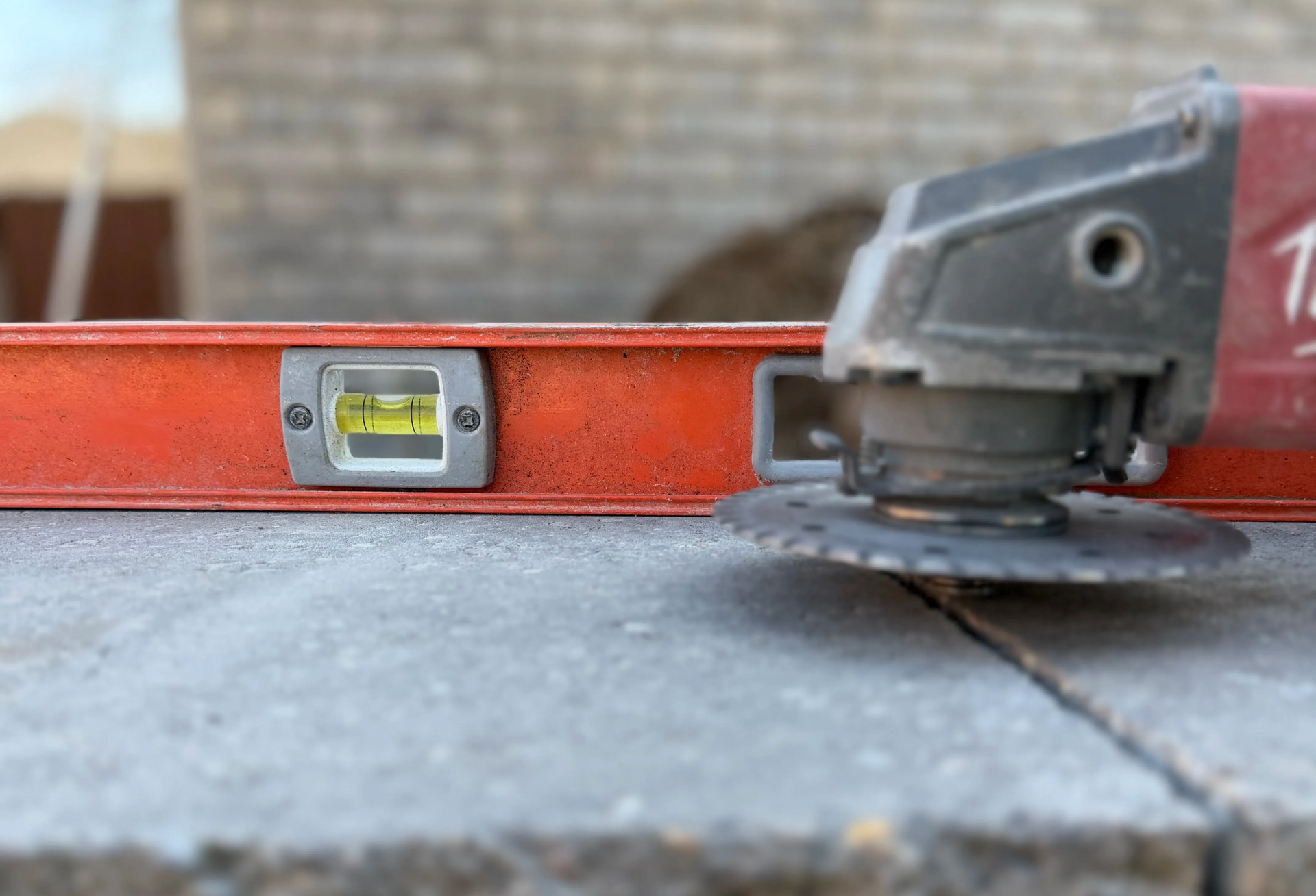 An orange level and a power tool sit on a grey stone surface for walkway leveling done right in springfield mo