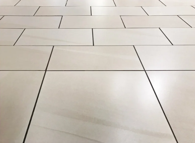 Light-colored tiled floor with dark grout lines and a slight reflection.