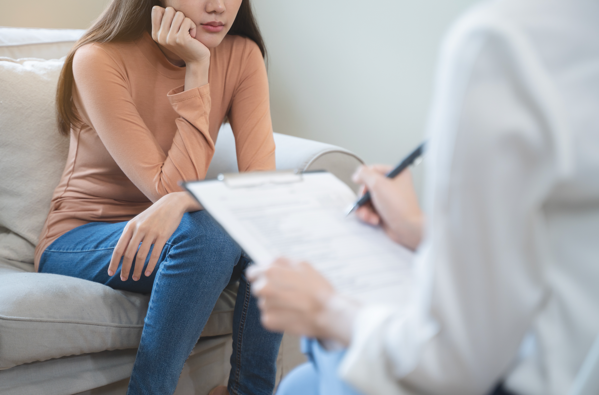 A woman is sitting on a couch talking to a doctor.