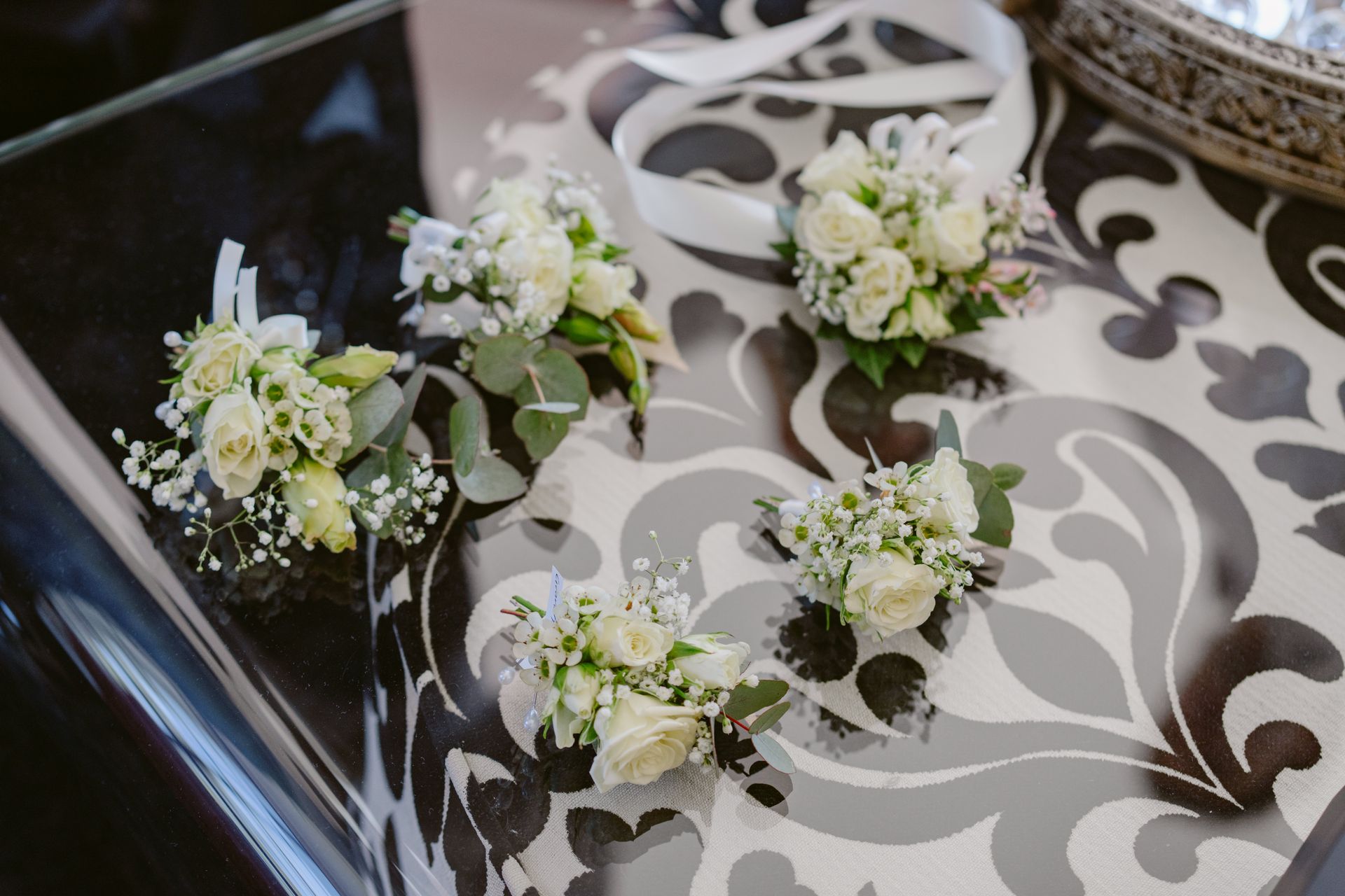 White floral boutonnieres arranged on a silver-and-brown patterned tray