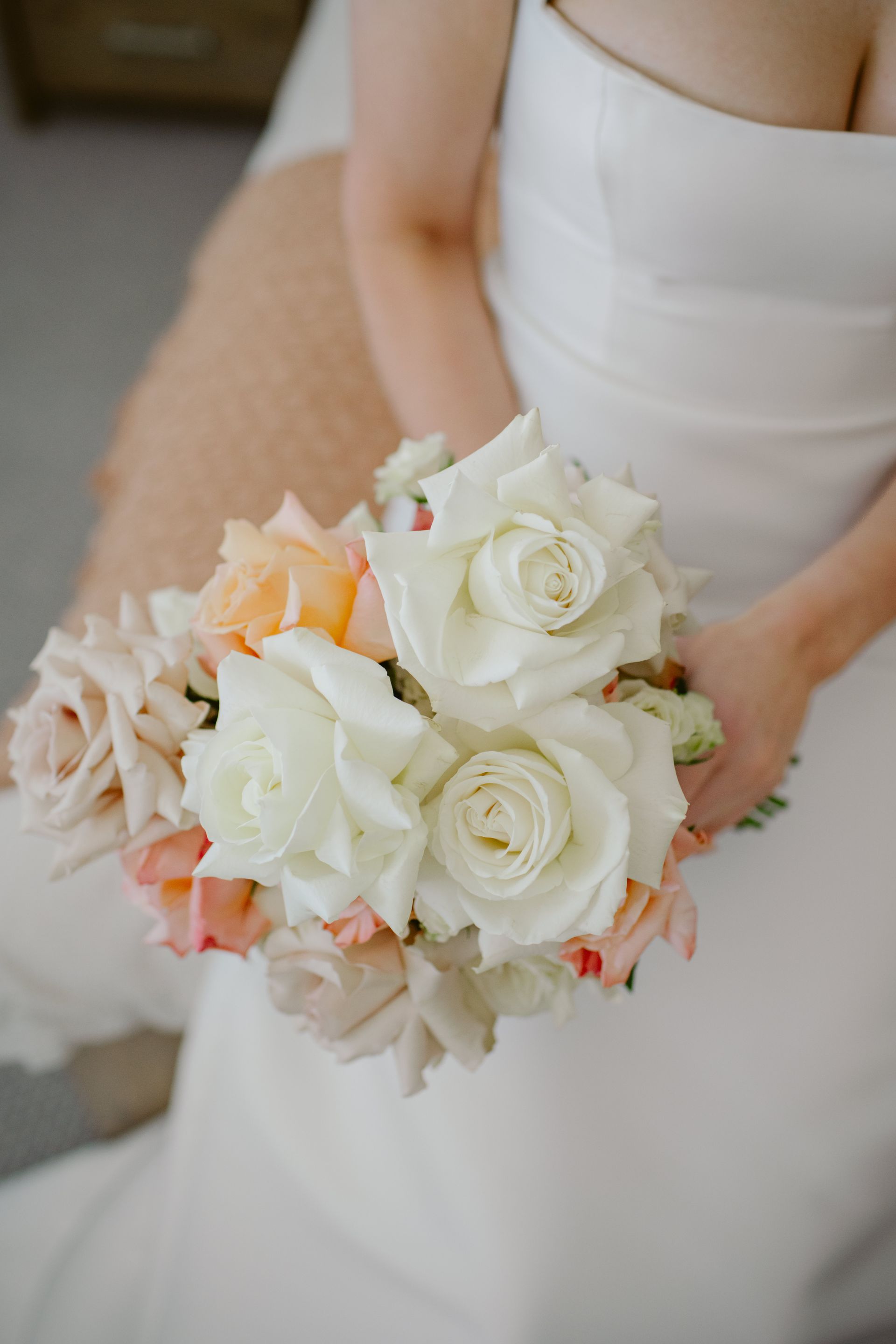 Bride holding a bouquet of white roses and blush flowers in a white wedding dress