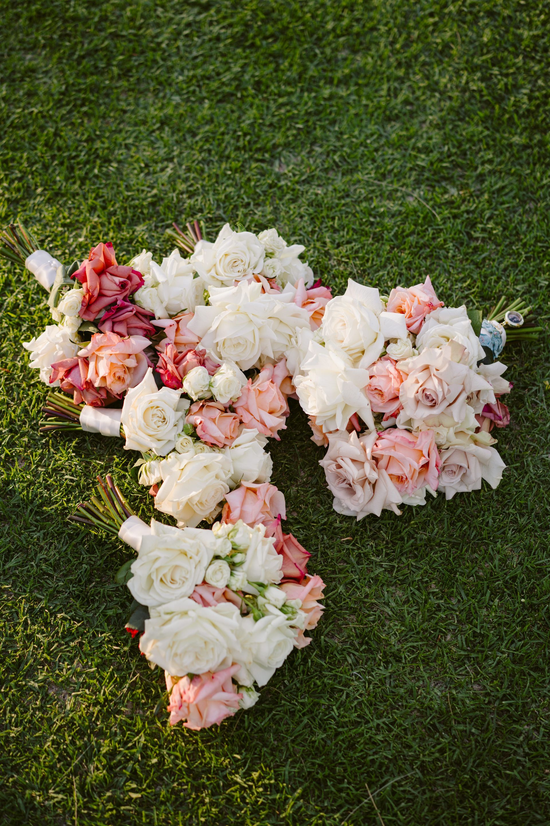 Pink and white flower arrangement in a cross shape on green grass
