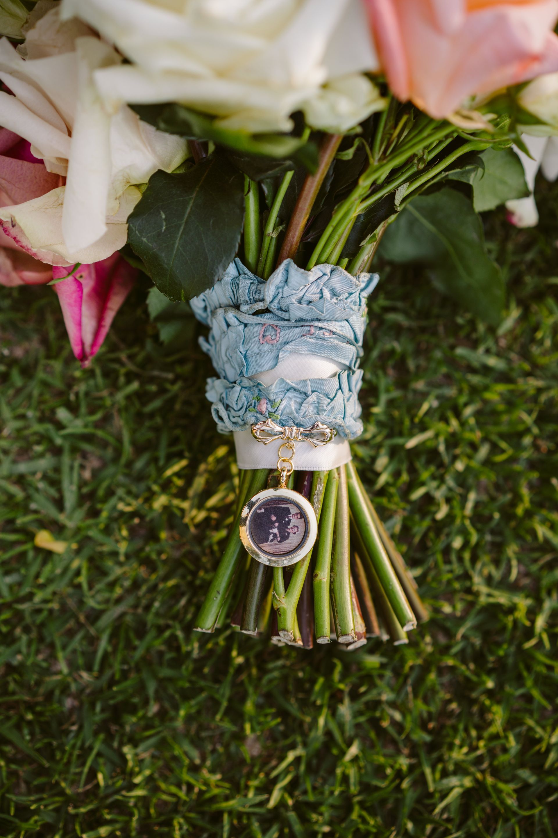 Blue watch wrapped around a bouquet of pink and white flowers on green grass