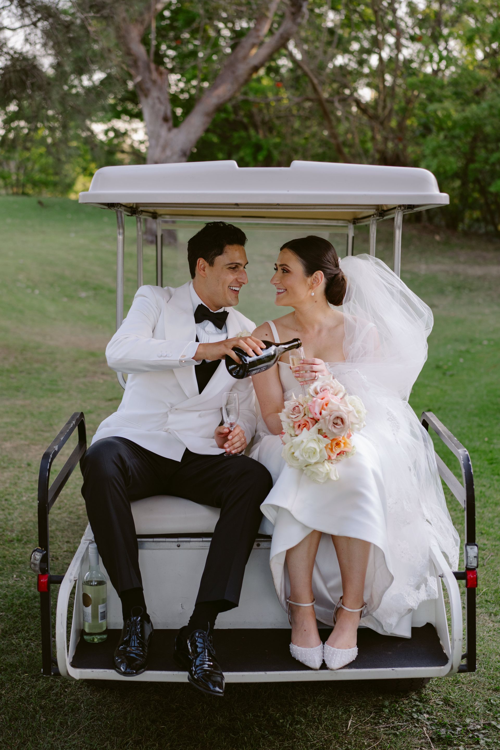 Bride and groom sharing a toast on a golf cart at an outdoor wedding