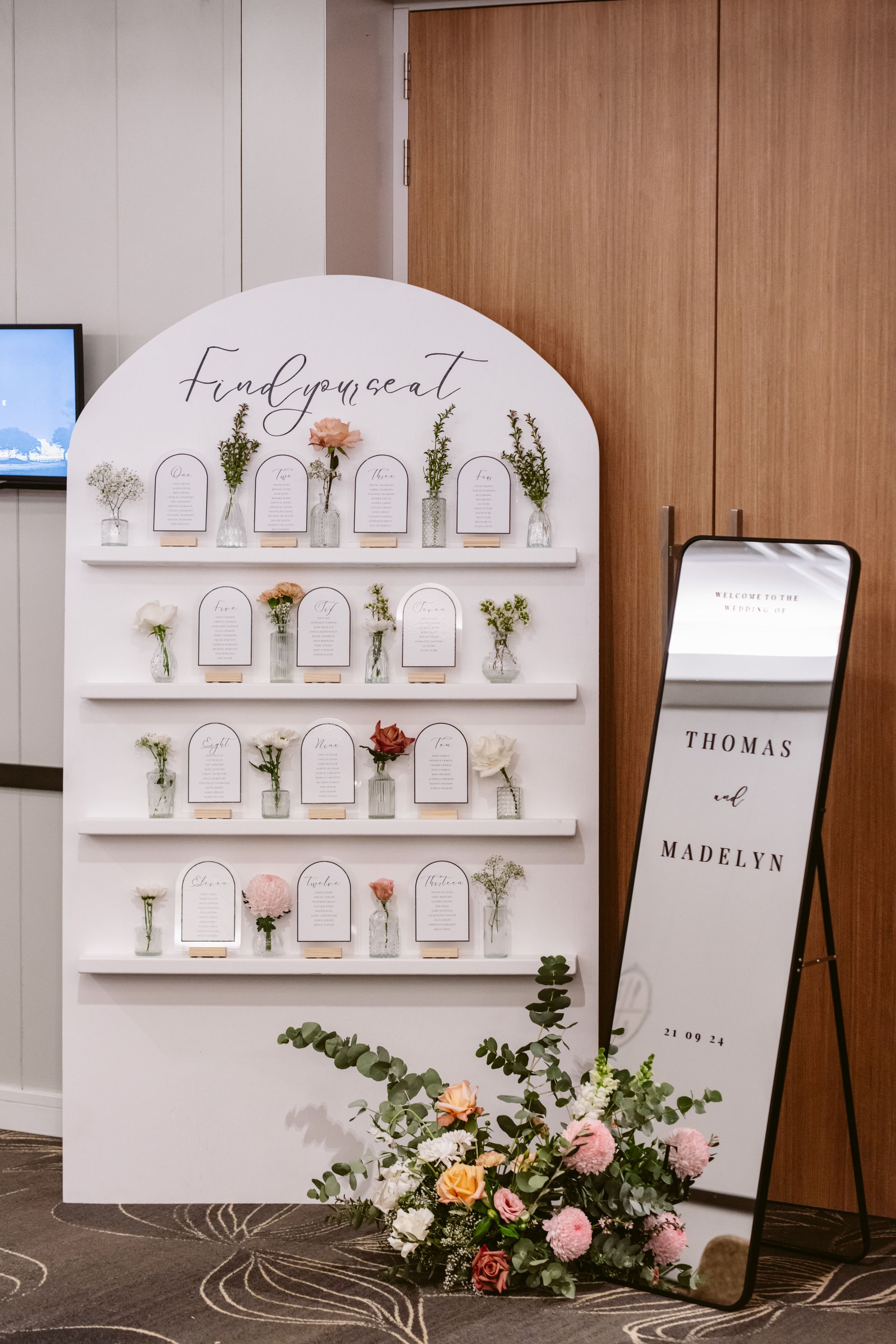 White display shelves with small products and flowers beside a standing sign in a boutique-like interior